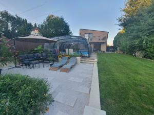a patio with a table and chairs and an umbrella at Paradise Vibe Balaton in Balatonkenese