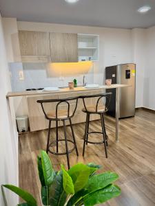 a kitchen with a counter and two stools and a refrigerator at Amazonía Luxury in Florencia