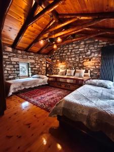 a bedroom with two beds and a stone wall at HerbStone Lodges in Asprangeloi
