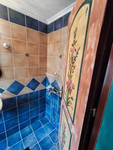 a bathroom with a shower with blue tiles and a door at HerbStone Lodges in Asprangeloi