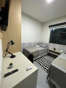 a room with two beds and a table with a lamp at Apartamento Completo localizado no centro in Matias Barbosa