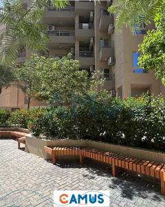 a park with benches in front of a building at CAMUS 354, Princess Resort in Hurghada +4 photos