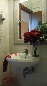 a bathroom with a sink with a vase of red roses at Agriturismo Castanito in Vico Equense
