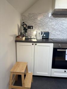 Una cocina con gabinetes blancos y un taburete de madera. en littoral, en Bruselas