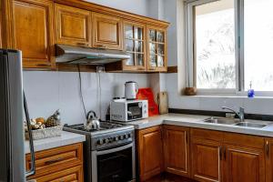 a kitchen with wooden cabinets and a stove top oven at Oceanfront Executive Serviced Apartment Mbezi Beach in Dar es Salaam