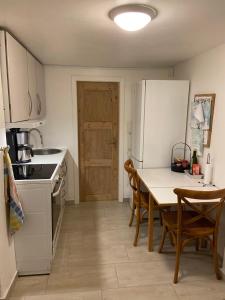 a kitchen with a table and a white refrigerator at Værelse med eget køkken og bad in Esbjerg