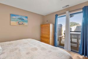 a bedroom with a bed and a dresser and a window at Sandpiper Cay 706 in Kitty Hawk