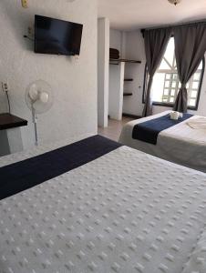 a hotel room with two beds and a flat screen tv at Hotel SPA Villa San Agustin in Tecozautla