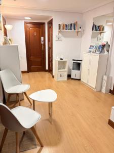 a living room with white chairs and tables and a door at Pensión Santa Clara in San Sebastián