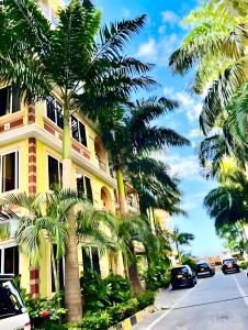 a yellow building with palm trees next to a street at Oceanfront Executive Serviced Apartment Mbezi Beach in Dar es Salaam