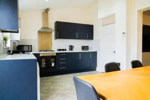a kitchen with black cabinets and a wooden table at 4 BD Sleeps 7 Parking WiFi in Coventry