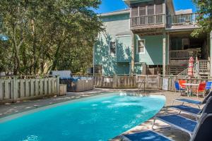 a swimming pool in a yard with chairs and a house at Dragonfly in Southern Shores