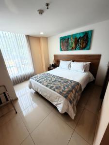 a bedroom with a bed and a painting on the wall at Ambar Hotel Boutique Cali in Cali