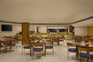 a dining room with wooden tables and chairs at The Fern Residency Ahmedabad, Subhash Bridge, Series by Marriott in Ahmedabad