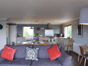 a living room with a blue couch and a kitchen at Morlich in Gairloch