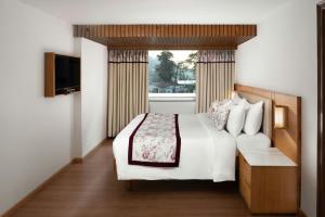 a bedroom with a white bed and a window at The Fern Brentwood Resort, Mussoorie, Series by Marriott in Mussoorie