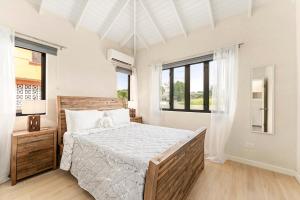 a white bedroom with a large bed and windows at Mullins Bay View - 4 Bed - Sea View, Infinity Pool in Saint Peter