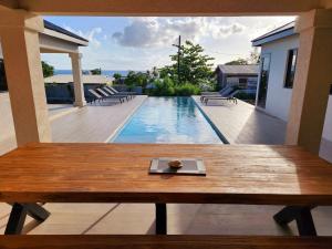 a wooden table on a patio with a swimming pool at Mullins Bay View - 4 Bed - Sea View, Infinity Pool in Saint Peter +6 photos