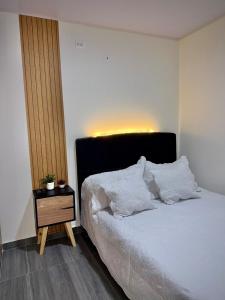 a bedroom with a bed with white sheets and a nightstand at Amazon Luxury Loft 201 in Florencia