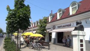 a building with tables and yellow umbrellas on a street at Easy Sleep - Comfy Stay in Soltvadkert