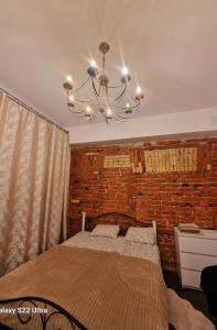 a bedroom with a brick wall and a chandelier at Kaunas Studios - RentA 18 in Kaunas