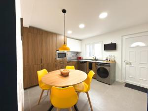 a kitchen with a wooden table and yellow chairs at Alma do Tejo - Alma Nossa in Montijo