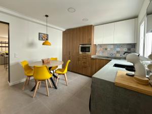 a kitchen with a table and some yellow chairs at Alma do Tejo - Alma Nossa in Montijo