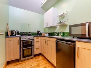 a kitchen with stainless steel appliances and wooden cabinets at Quinag Studio Apartment - Uk49098 in Inchnadamph