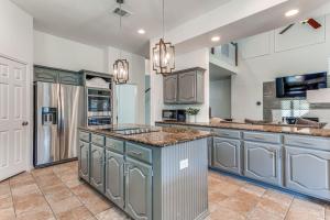 a large kitchen with gray cabinets and a large island at 5Br Lux! Pool, Games & Theater in Rowlett