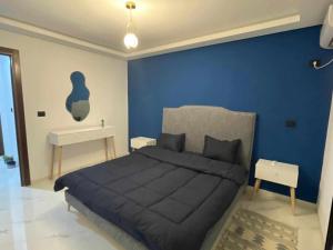 a blue bedroom with a bed and a blue wall at Cerises in El Aouina Station