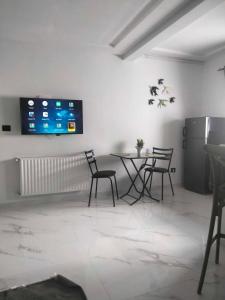 a room with a table and chairs and a tv on the wall at Cerises in El Aouina Station