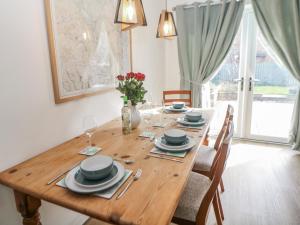 a wooden table with plates and glasses and a vase of flowers at Win Hill View in Bamford