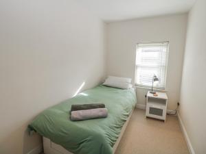 a small bedroom with a green bed and a window at Win Hill View in Bamford