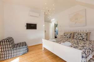 a white bedroom with a bed and a chair at Jezerska Villa in Ogulin +19 photos
