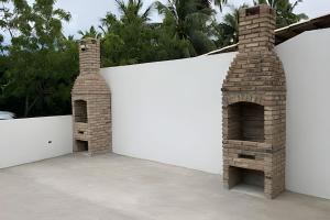 a white wall with two brick chimneys on a patio at PARAISO A BEIRA Mar de Antunes, conforto,Piscina,Mar e Natureza in Maragogi