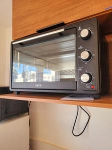 a black toaster oven sitting on a wooden shelf at Apartamento com estacionamento in Uruguaiana +11 photos