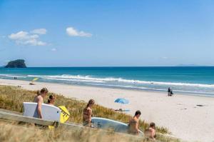 a group of people on a beach with a bath tub at Oceanside to Seaside 334 in Mount Maunganui