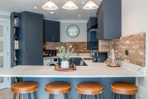 a kitchen with blue cabinets and a counter with stools at 2 Bed Flat in Woking Central in Woking