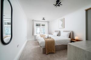 a white bedroom with a bed and a mirror at 2 Bed Flat in Woking Central in Woking