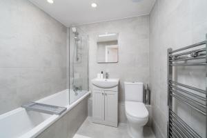 a bathroom with a toilet and a sink and a tub at 2 Bed Flat in Woking Central in Woking +51 photos