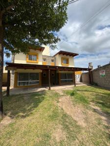 a yellow house with a tree in front of it at Complejo El Teyu in Miramar