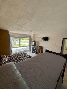 a bedroom with a bed and a large window at Complejo El Teyu in Miramar