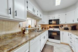a kitchen with white cabinets and a sink at Charming Condo Sleeps 6 Shared Pool Gym Fireplace in Gatlinburg