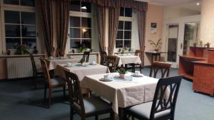 GrillenburgにあるPension am Tharandter Waldの白いテーブルクロスのテーブルと椅子が備わるレストラン