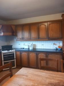 a kitchen with wooden cabinets and a table with chairs at Fiona's Country Accommodation in Murphyʼs Bridge