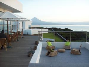 uma varanda com cadeiras e mesas e vista para o oceano em Cantinho das Buganvilias AT**** em Queimada