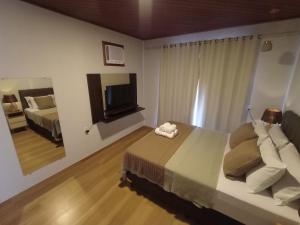 a bedroom with a bed and a flat screen tv at Casa em Pedra Azul in Domingos Martins