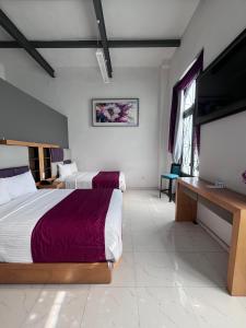 a bedroom with two beds and a flat screen tv at Hotel Alhaja Puebla Centro Histórico in Puebla