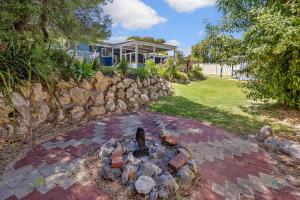 a brick patio with a fire pit in front of a house at Barefoot on O'Neil in Lancelin