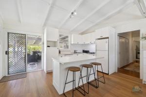 a kitchen with white cabinets and bar stools at Barefoot on O'Neil in Lancelin +24 photos